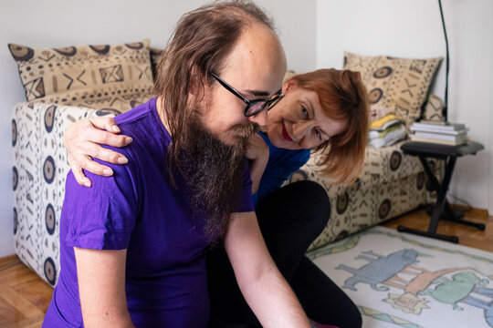 Adult son and his mum sitting on the floor at home.