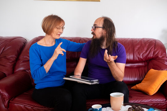 The adult son and his mum having a conversation in the living room.