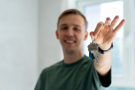 Close up male hand holding key from new home / apartment. 
