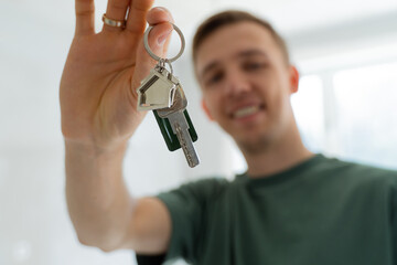 Close up male hand holding key from new home / apartment. 