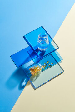 Glass of water and pills from a jar on blue and yellow backgrounds