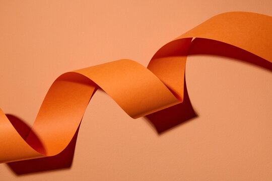 Orange curl ribbon streamer on color background