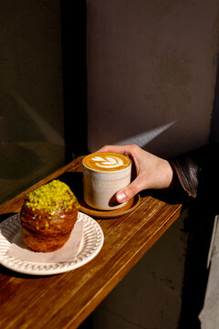 A young anonymous person's hand holding a cup of flat white coffee
