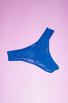 Royal blue mesh underpants on a pink background with direct flashlight