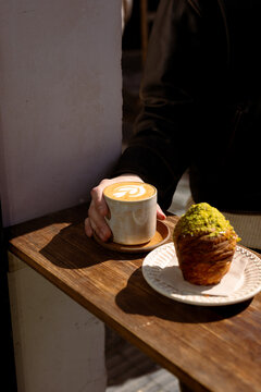 Man holding a flat white coffee cup outside a specialty coffee shop