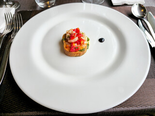 A small plate of food sits on a table with a fork and knife. The plate is almost empty, with only a small portion of food remaining. The food appears to be a sandwich