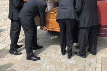 Men of funeral service loading the coffin into the hearse