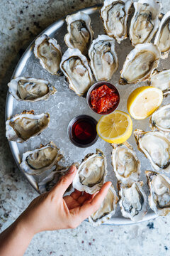 Person taking one oyster from  Plate of Oysters