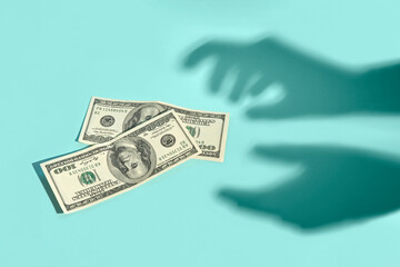 Invisible hands reaching for dollar bills, casting shadows. 