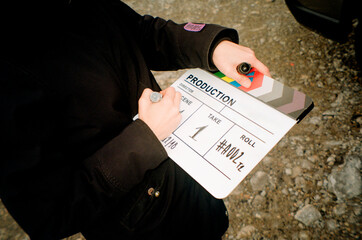 An audiovisual production team member writing down on a clapperboard