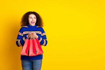 Portrait of astonished girl with wavy hair wear knit pullover holding shopping bags look empty...