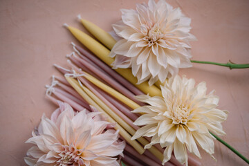 Dahlias and candles on pastel surface