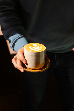 Barista holds a cup of specialty flat white coffee