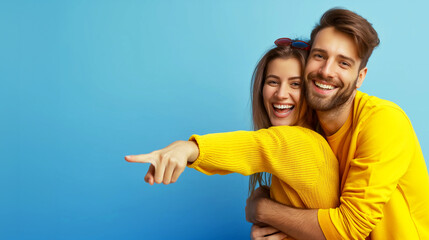Fototapeta premium Happy couple in yellow outfits smiling and pointing against blue background. Copy space. Generative AI 