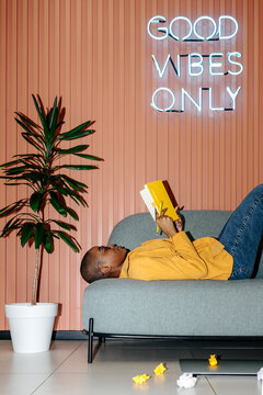 Woman reading notes in notebook lying on sofa