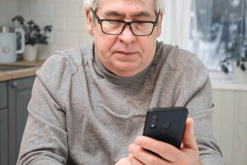 Hoary old man looking at web camera, holding phone, talking with children, wife online. Senior grandpa smiling chatting with friends, family via video call. Modern technologies and older generation
