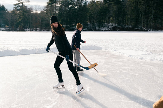 young people  skating and playing hockey on a lake in New England 
