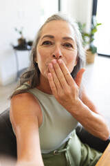 At home, Caucasian mature woman blowing kiss during video call