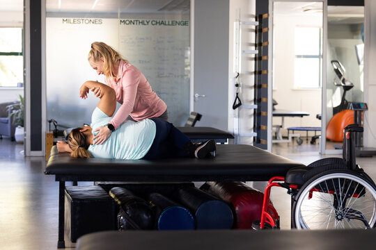 At rehab center, Caucasian female therapist treats biracial female paraplegic patient
