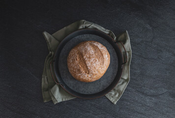 One rye round bread on a black background.