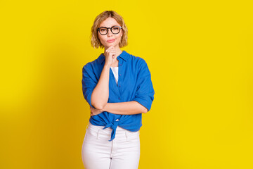Photo of nice young girl think empty space wear blue shirt isolated on yellow color background