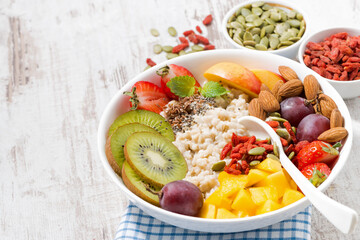 oatmeal porridge with fresh fruits and superfoods and white wooden background