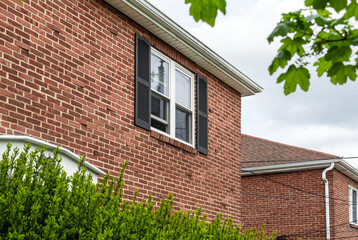 Old house brick wall with new window and fixed decorative shutter, Brighton, MA, USA