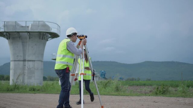 Civil engineer on construction site with survey instrument. woman work with leveling  camera on site construction background. Couple worker on site construction.