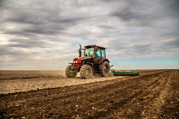 Powerful tractor at work, turning over soil on a vast farmland under a clear sky