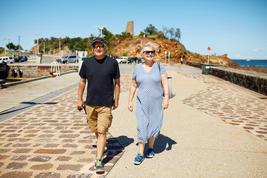 Smiling couple walks along the promenade by the sea