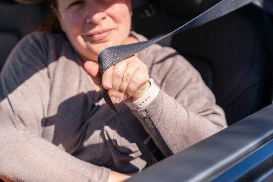 woman putting on car seatbelt
