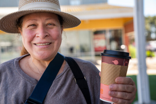 Smiling woman with to go cup at shopping plaza