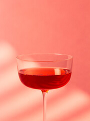 A sleek and elegant image of a cocktail glass filled with red liquid against a vibrant pink background. This modern composition is perfect for themes of elegance, style, and sophisticated beverages.