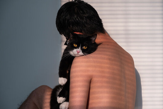 Lonely young man let the cat rest its head on his skin