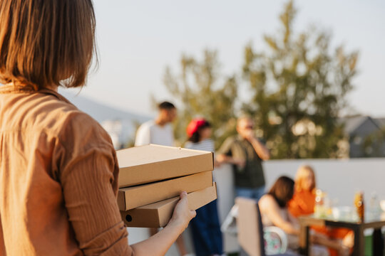 Woman carrying pizza boxes for friends on terrace