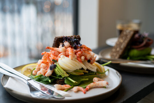 Fancy breakfast sandwich in cafe with shrimps, eggs and spinach