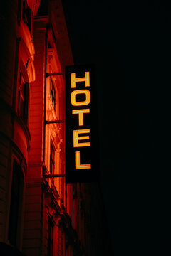 Red "HOTEL" glowing neon sign at night on the building facade