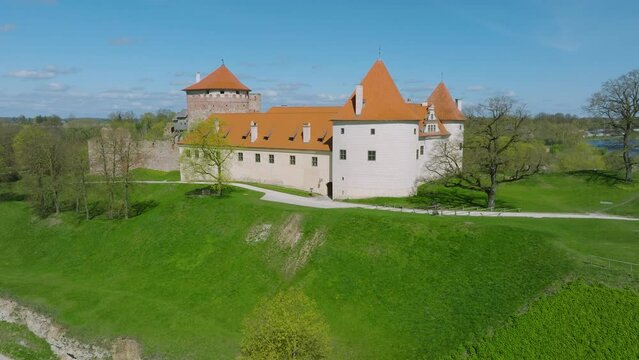 Aerial establishing view of Bauska Medieval Castle and ruins, Musa and Memele rivers next to the castle, sunny spring day, ascending drone shot moving forward