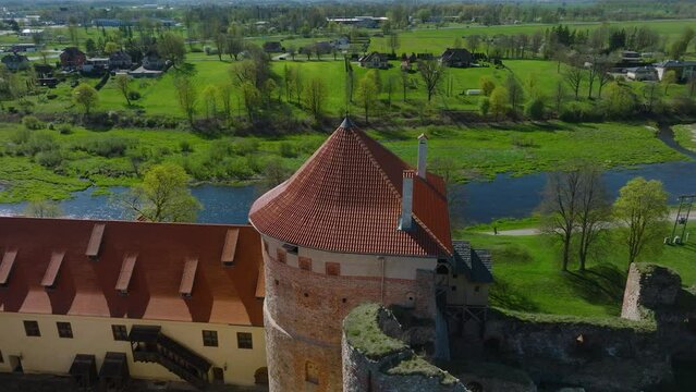 Aerial establishing view of Bauska Medieval Castle tower and ruins, Musa and Memele rivers next to the castle, sunny spring day, orbiting drone shot