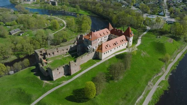Aerial establishing view of Bauska Medieval Castle and ruins, Musa and Memele rivers next to the castle, sunny spring day, wide drone shot moving backward, camera tilt up