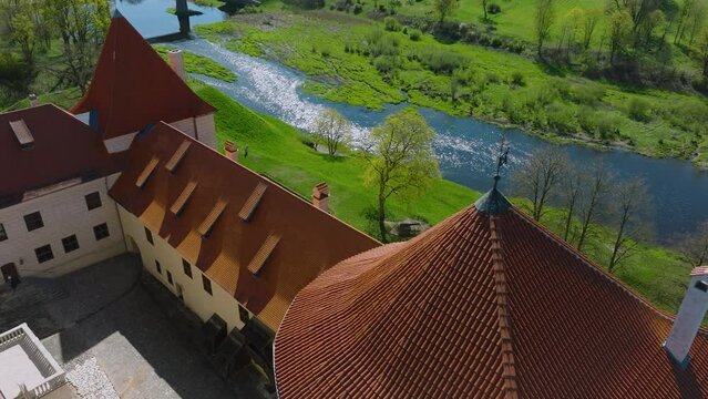 Aerial establishing view of Bauska Medieval Castle and ruins, Musa and Memele rivers next to the castle, sunny spring day, medium drone shot moving forward, tilt down