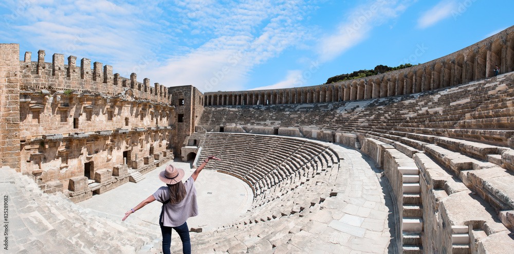 Wall mural happy woman in hat open arms in free happiness standing and posing - roman amphitheater of aspendos,