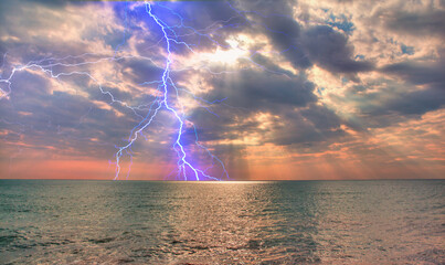 Beautiful landscape with lightning over the calm sea at sunset 