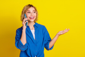 Portrait of pretty young lady speak phone wear blue shirt isolated on yellow color background