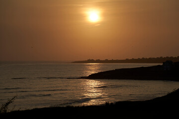 Sunset over the coast in France. Village silhouette by the sea in Brittany. Landscape ideal as background for postcard.