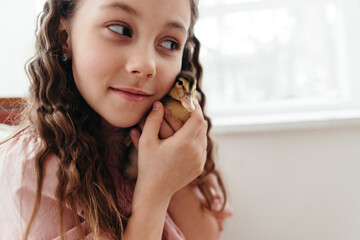 Smiling girl gently holds the Duckling indoors
