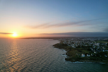 Landscape of sunset over village near the coast by the sea. Aerial view with the drone. France, Brittany.