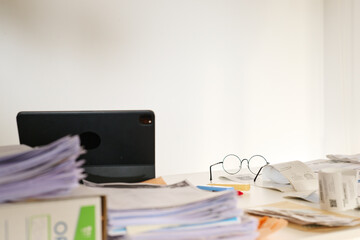 Messy office desk with paperwork and glasses.