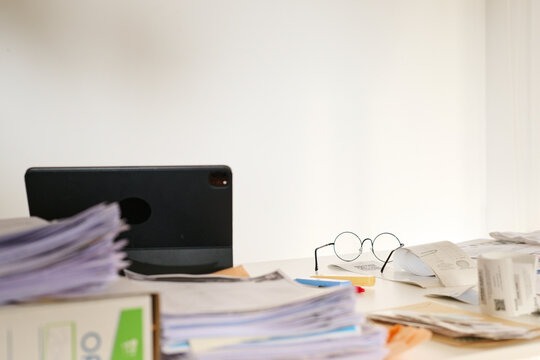 Messy office desk with paperwork and glasses.