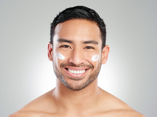 Portrait, wellness and man with cream, skincare and dermatology on grey studio background. Face,...